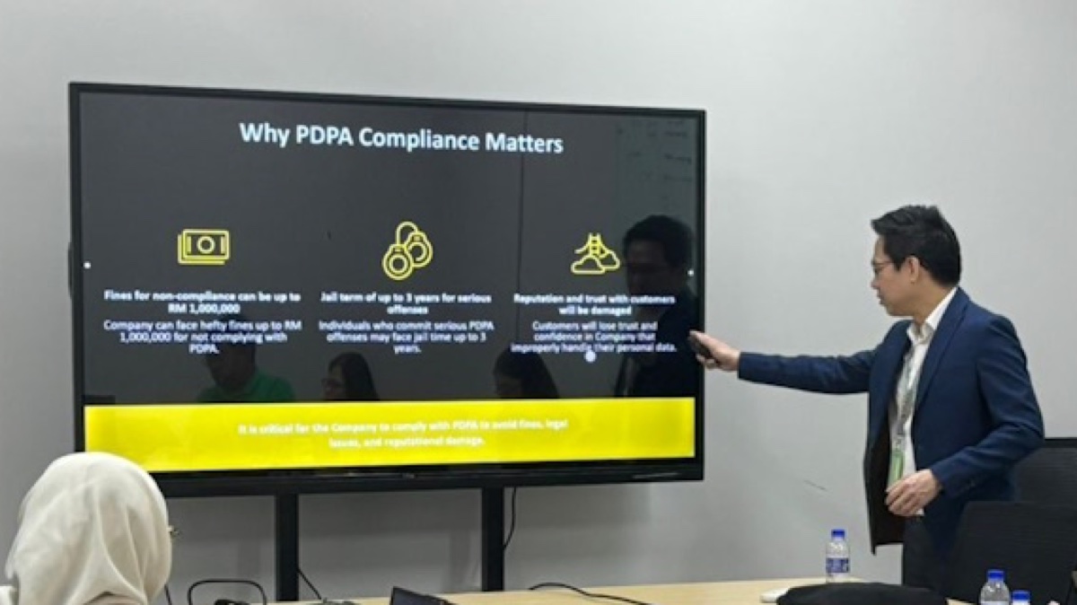 Edwin Lee presenting PDPA penalties to a management team, beside a slide reading “Why PDPA Compliance Matters” setting out fines of up to RM1,000,000 and up to 3 years' imprisonment
