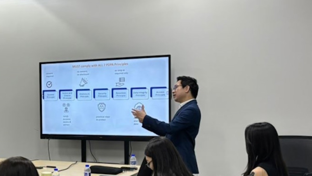 Edwin Lee briefing a management team on the seven PDPA data protection principles, beside a slide reading “MUST comply with ALL 7 PDPA Principles”